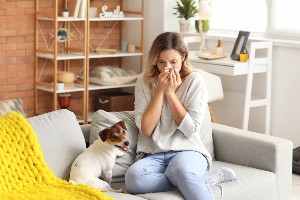 woman sneezing next to dog
