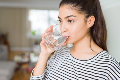 young woman drinking a glass of water at home